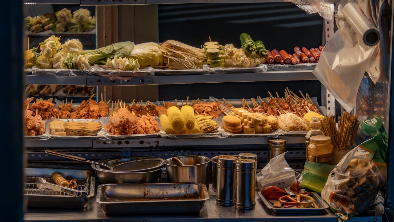 about-us-01 Vibrant street food stall with diverse skewers, vegetables, and condiments on display.